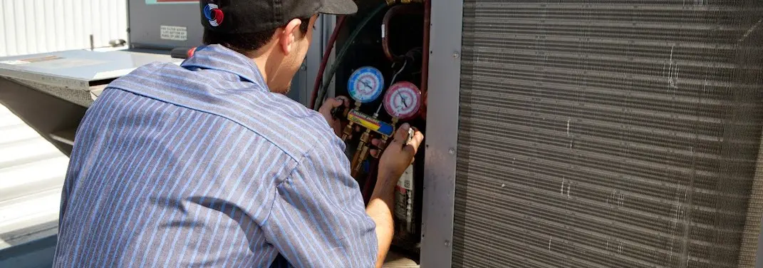 HVAC technician servicing a condenser unit in Meriden